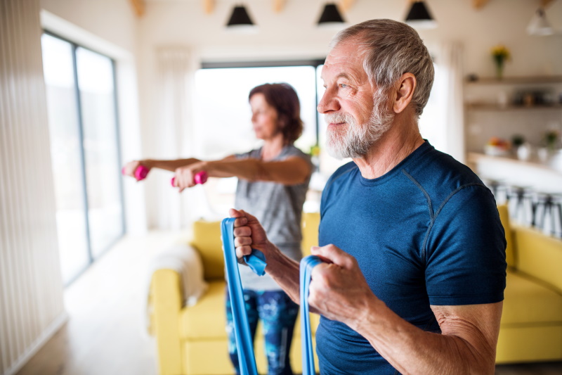 A happy senior couple indoors at home, doing exercise indoors. - Vorteilhaft Leben - Vorteilhaft Leben