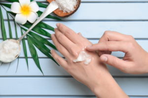 Young woman applying coconut oil on wooden background, closeup - Vorteilhaft Leben - Vorteilhaft Leben