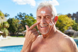 Senior Mann cremt sein Gesicht mit Sonnencreme ein im Urlaub im Sommer - Vorteilhaft Leben - Vorteilhaft Leben