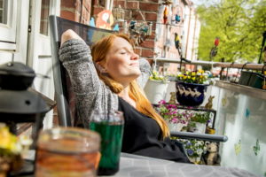 Eine Frau liegt im Gartenstuhl und genießt die wärmenden Sonnenstrahlen.