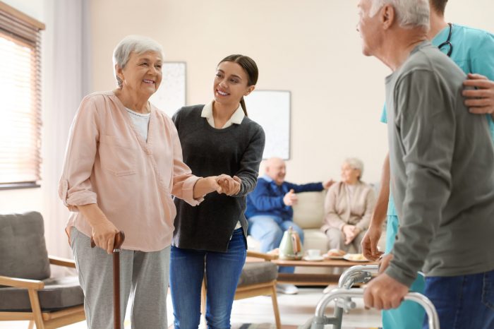 Care workers helping to elderly patients to walk in geriatric ho #image_title